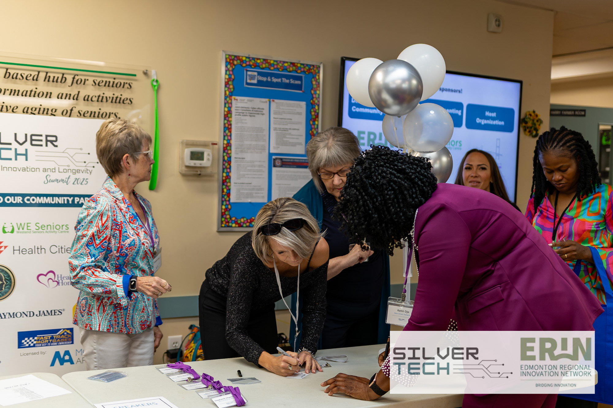 Attendees signing in at the SilverTech Summit registration table with community partner banner