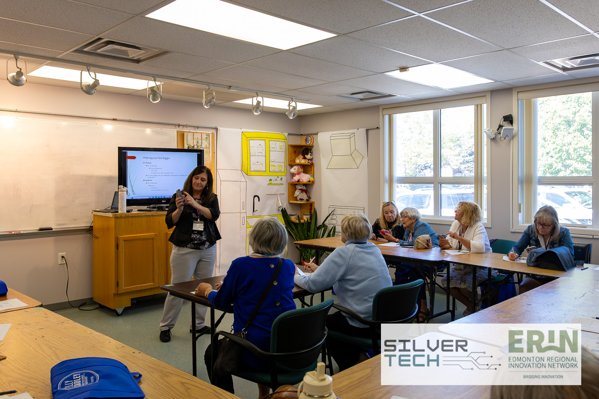 Presenter demonstrating phone accessibility settings to seniors in a breakout session